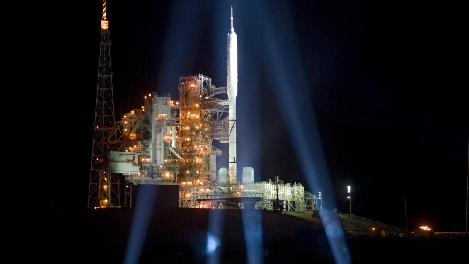 The Ares I-X rocket lit by xenon lights on Launch Complex 39B at nightfall, October 2009