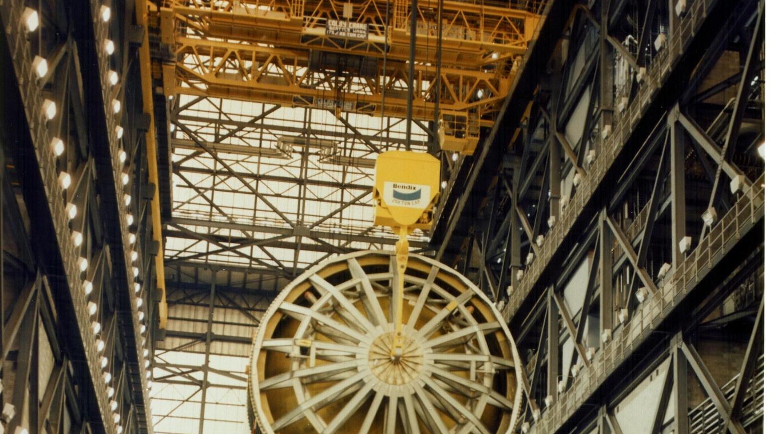 An overhead crane lifts the Saturn V first stage for Apollo 11 inside the Vehicle Assembly Building, 1969